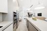 Kitchen featuring flat-panel cabinetry, a spacious island with a solid surface countertop, stainless steel double wall ovens, a side-by-side refrigera