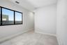 Neutral-toned tile flooring, oversized window with black frame, and smooth-finish walls