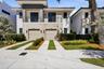 Modern exterior featuring a stacked stone facade, metal-accented second-story balcony with railings, dual two-car garage doors, and concrete paver dri