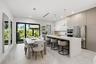 Kitchen featuring a waterfall-edge island with solid-surface countertops, floor-to-ceiling flat-panel cabinetry, stainless steel built-in appliances, 