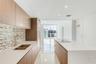 Kitchen featuring wood-finish cabinetry, stone-surface countertops, mosaic tile backsplash, integrated stainless steel appliances, and a central islan