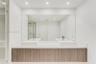 Floating vanity with wood-finish cabinetry, dual square vessel sinks, white countertop, and large wall-to-wall mirror with recessed ceiling lighting