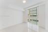 Room featuring polished tile flooring, white walls, recessed ceiling lighting, and large sliding windows with exterior horizontal louvers