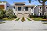 Contemporary two-story exterior featuring a horizontal-slat facade, stone veneer detailing, metal balcony railing, and two integrated garage doors