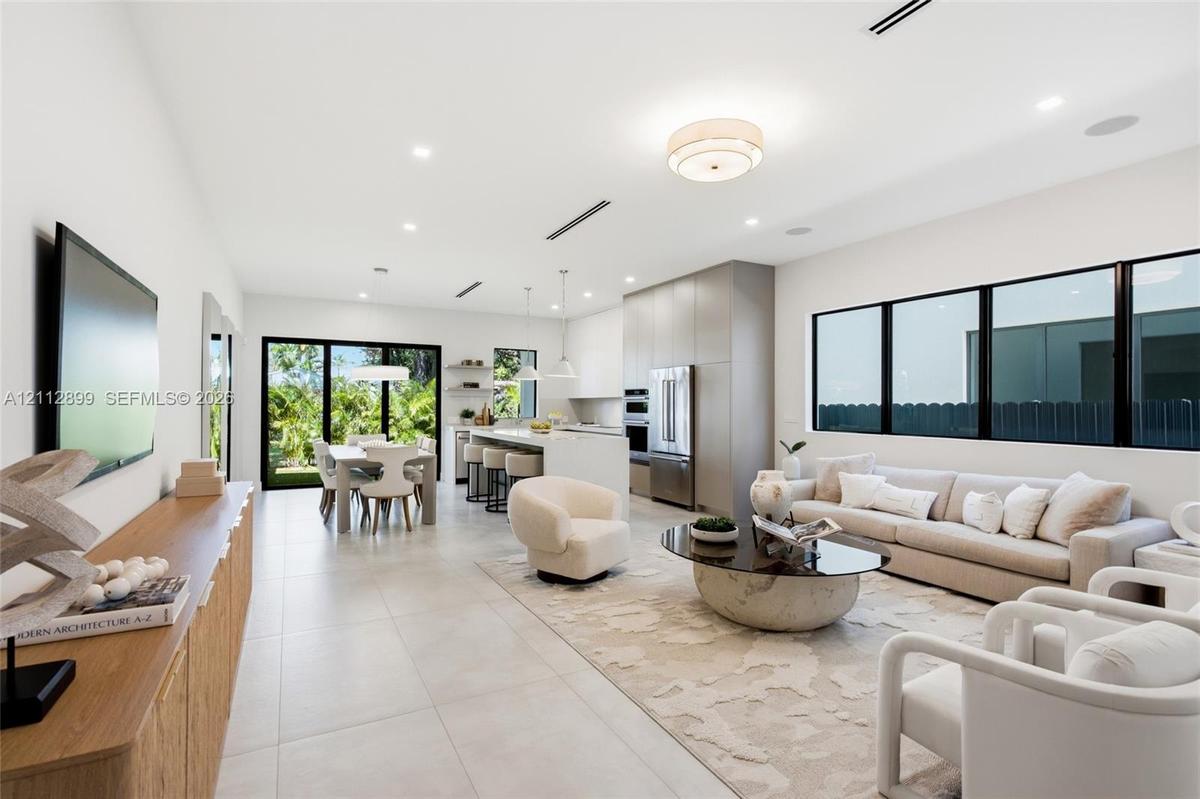 Open-concept interior featuring large-format tile flooring, recessed ceiling lighting, built-in kitchen cabinetry, stainless steel appliances, and bla