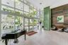 Grand entrance lobby featuring double-height glass curtain walls, floor-to-ceiling windows, large-format tile flooring, a vibrant green accent pillar,