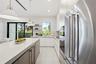 Kitchen featuring quartz countertops, flat-panel cabinetry, stainless steel built-in appliances, a wine refrigerator, and pendant lighting