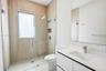 Modern bathroom featuring a glass-enclosed shower with vertical-tile surround, built-in recessed wall niche, wall-to-wall mirror, and white vanity wit