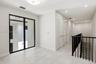 Large-format tile flooring, black-framed floor-to-ceiling glass window, recessed lighting, and a staircase with a black metal railing