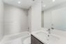 Bathroom featuring a large-format tiled shower surround with a rain-style showerhead, a deep soaking tub, and a vanity topped with a rectangular integ