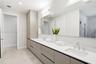 Extended vanity featuring flat-panel cabinetry, light-toned solid surface countertops, dual undermount sinks, and a large-format vanity mirror with in