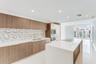 Kitchen featuring wood-finish cabinetry, quartz countertops, mosaic tile backsplash, built-in wall oven and microwave, and a large center island with 