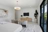 Neutral-toned interior featuring large-format tile flooring, a contemporary drum pendant light fixture, and black-framed sliding glass doors opening t