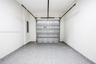 Enclosed garage space featuring a metal overhead door, seamless speckled epoxy flooring, and crisp white wall finishes