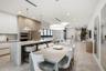 Open-concept kitchen featuring flat-panel cabinetry, a waterfall-edge stone island, built-in double ovens, and large-format tile flooring