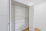 Built-in closet organizer featuring white shelving, integrated drawers, and dual hanging rods