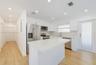 Kitchen featuring white flat-panel cabinetry, a central island with a quartz countertop, stainless steel appliances, and wood-finish flooring