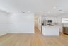 Open-concept interior featuring light wood-finish flooring, recessed lighting, white gloss cabinetry, quartz countertops, and stainless steel applianc