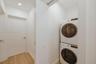 Stacked washer and dryer unit with wood-finish flooring and recessed lighting