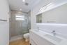 Double vanity with a white countertop and rectangular undermount sinks, illuminated mirror with integrated backlighting, wood-finish flooring, and a w