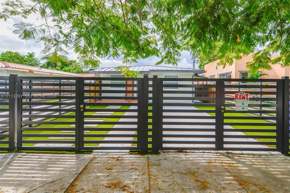 Horizontal slat metal entry gate with concrete paver walkway and synthetic turf lawn