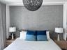 Textured gray wall accent, recessed built-in wood-finish nightstands, and spherical overhead pendant light fixture