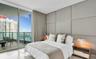 Floor-to-ceiling glass panel windows, expansive stone balcony with metal railing, and custom upholstered wall paneling