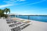 Waterfront deck featuring a white pergola, composite decking, and direct access to the water with mounted ladders