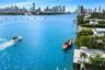 Waterfront property featuring a private boat dock, swimming pool, concrete patio, and direct waterway access with a backdrop of the city skyline