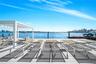 Waterfront dock featuring light-toned decking, a white pergola, and integrated marine pilings