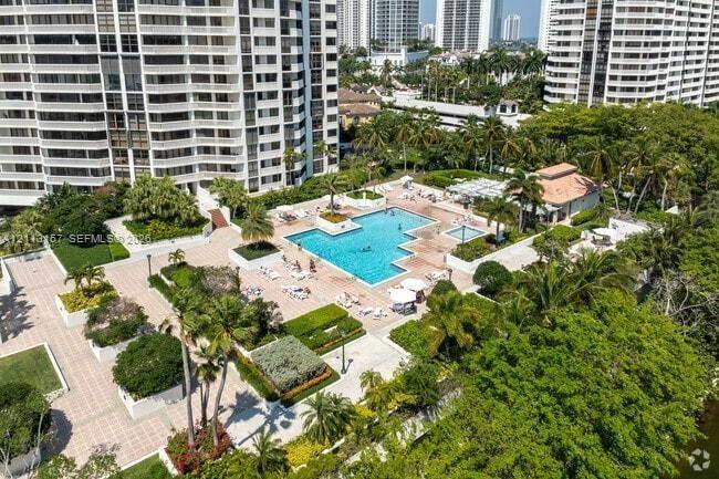 Outdoor swimming pool with integrated spa, paved terrace, and manicured landscaping featuring mature palm trees