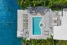 Waterfront deck featuring a swimming pool with integrated circular spa, light-toned decking material, and a pergola structure