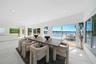 Open-concept interior featuring large-format tile flooring, recessed lighting, and expansive floor-to-ceiling glass sliding doors opening to an outdoo