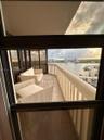 Private balcony featuring tile flooring, metal railings, floor-to-ceiling glass paneling, and water-fronting scenery