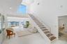 Open-concept interior featuring high ceilings, open-riser staircase with stainless steel cable railing and wood-finish treads, large-format tile floor