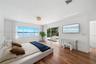 Hardwood flooring, expansive horizontal windows, recessed ceiling lighting, and sliding glass doors opening to a balcony