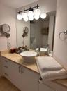 Bathroom vanity featuring a light-toned stone countertop, white cabinetry with metallic hardware, a vessel sink with a single-handle chrome faucet, an