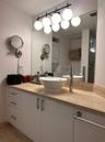 White vanity cabinet with stone countertop, elevated vessel sink, high-arc chrome faucet, and multi-light glass globe fixture