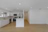 Kitchen featuring white high-gloss cabinetry, stainless steel appliances, a peninsula with stone countertops, and wood-finish flooring illuminated by 