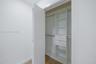 Custom closet featuring white built-in cabinetry, dual drawers, integrated shelving, and metal hanging rods over wood-finish flooring