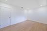 Neutral interior space featuring wood-finish flooring, crisp white walls, and recessed ceiling lighting