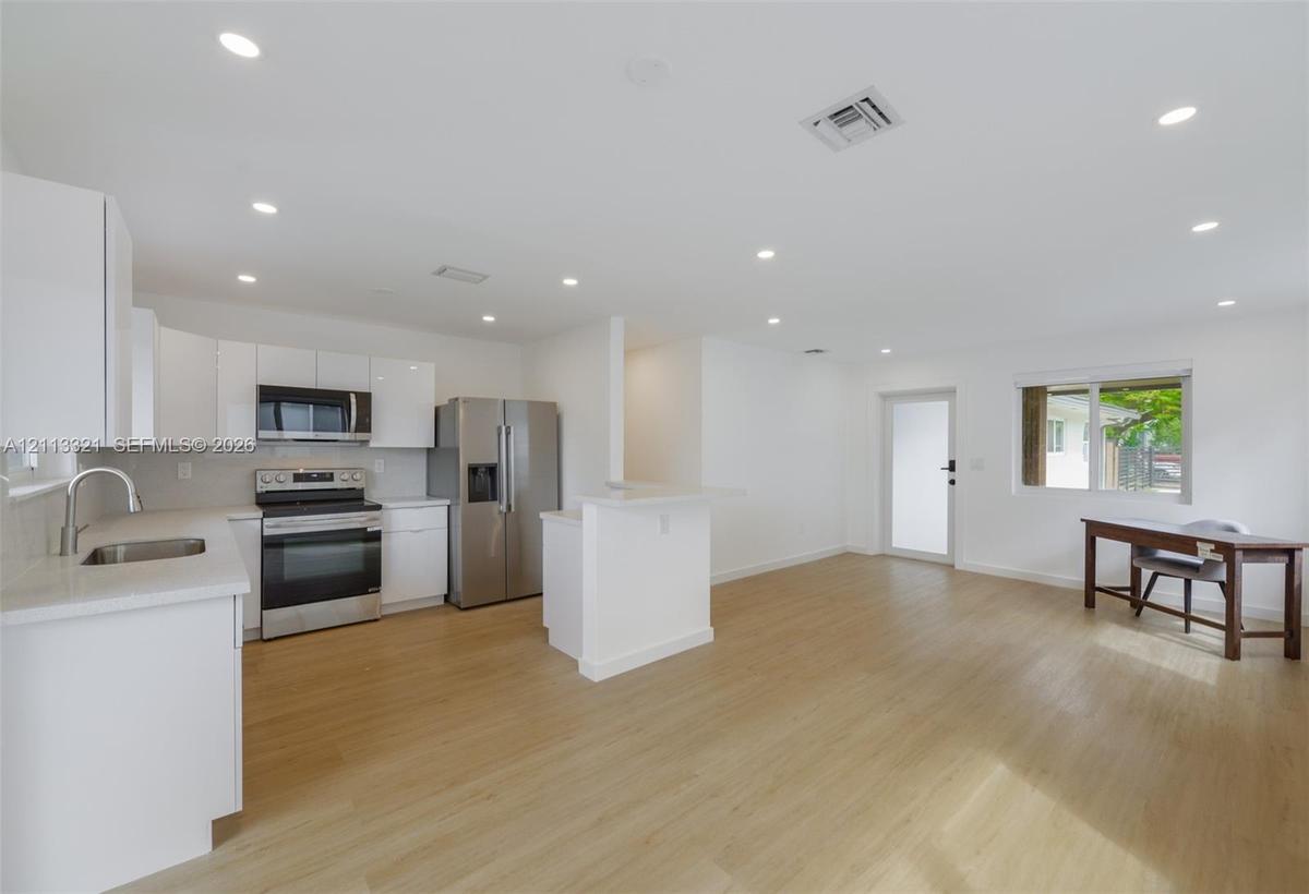 Kitchen featuring white cabinetry, stone countertops, stainless steel appliances, recessed lighting, and wood-finish flooring