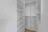 Walk-in closet featuring white built-in shelving, integrated hanging rods, soft-close drawer units, and wood-finish flooring