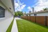 Side yard featuring synthetic turf, a concrete walkway, inset pavers, and a horizontal wood-composite privacy fence