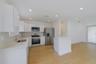 Kitchen featuring high-gloss white cabinetry, stone-finish countertops, stainless steel appliances, recessed lighting, and wood-finish flooring
