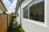 Exterior side yard featuring horizontal composite privacy fencing, synthetic turf, a stucco facade, and aluminum-framed windows