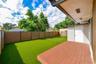 Backyard featuring a synthetic turf lawn, composite wood-finish decking, horizontal slat privacy fencing, and an exterior storage closet