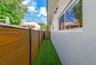 Exterior side yard featuring artificial turf, a horizontal wood-finish privacy fence with metal posts, and smooth-finish stucco siding