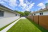 Exterior side yard featuring synthetic turf, concrete paver path, wood-finish privacy fencing, and metal gate