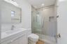 Bathroom featuring a white vanity with a countertop basin, a frameless glass shower enclosure with sliding doors, a recessed wall niche, and large-for